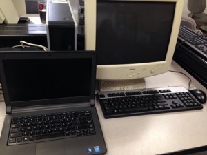 Unit 5 student laptop standing by a computer commonly found in a school computer lab.